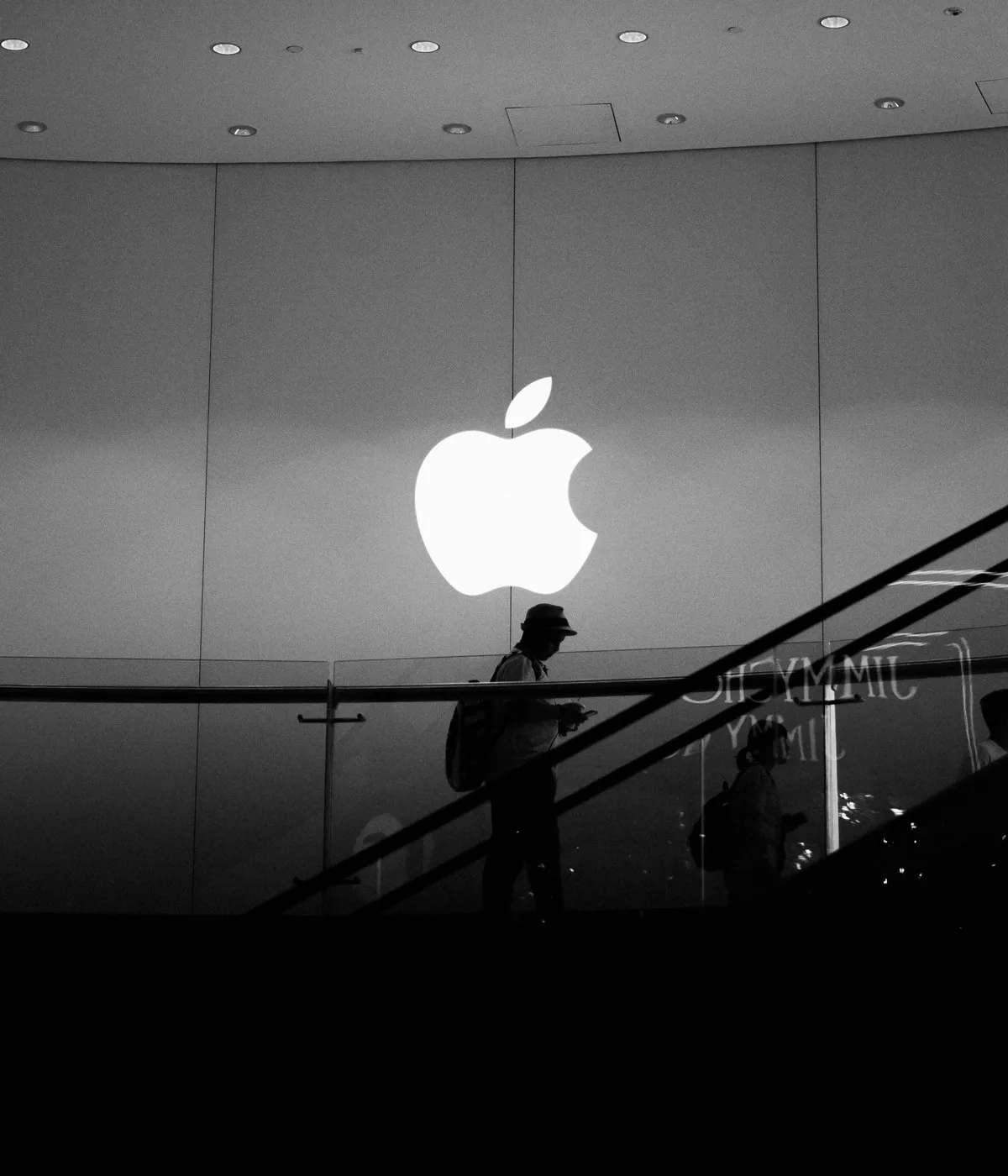 Logo Apple lumineux, personne en silhouette.