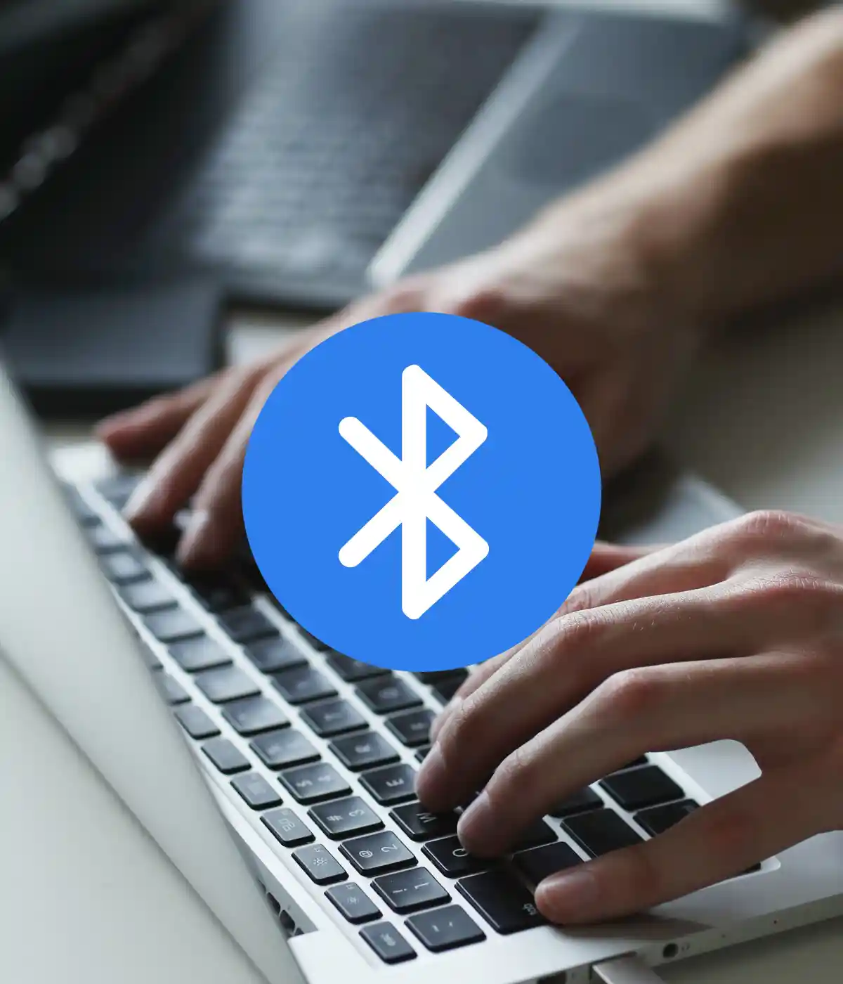 Mains tapant sur un clavier, logo Bluetooth.