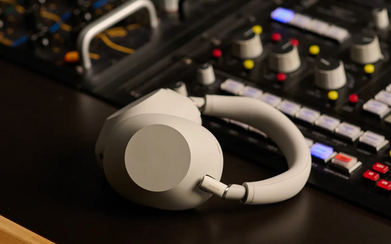 Casque audio blanc devant une table de mixage.