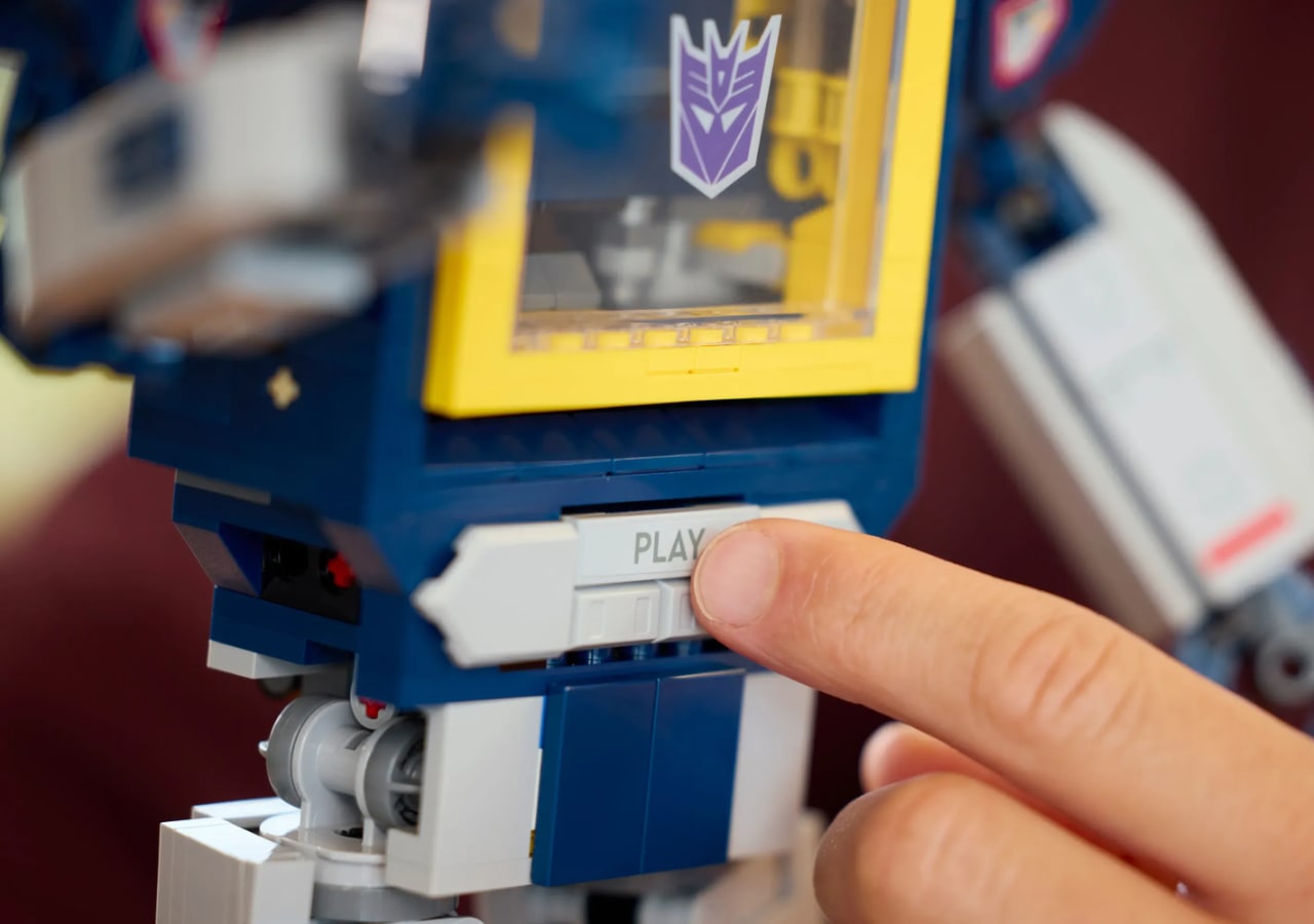 Main appuyant bouton play sur jouet robot.