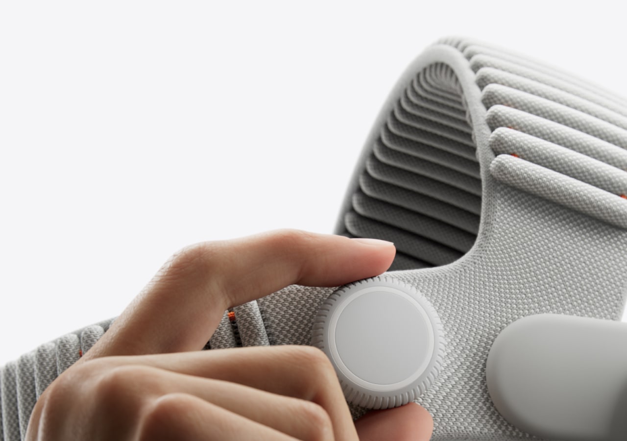 Main ajustant une molette sur un dispositif gris.