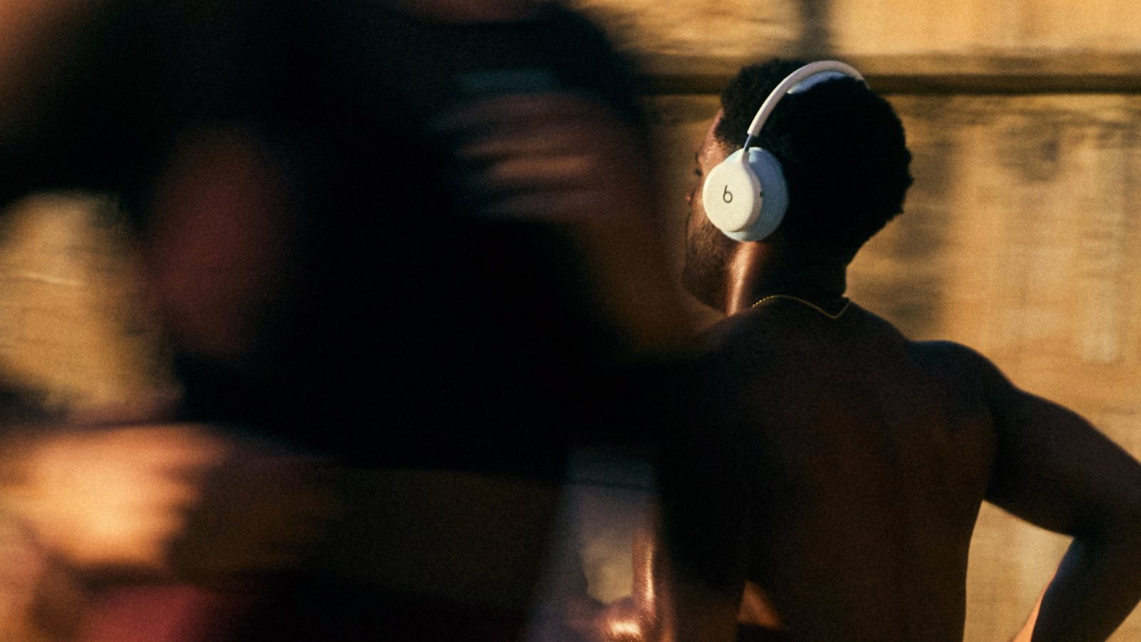 Athlète torse nu vu de dos portant un Beats 360 blanc pendant l'entraînement