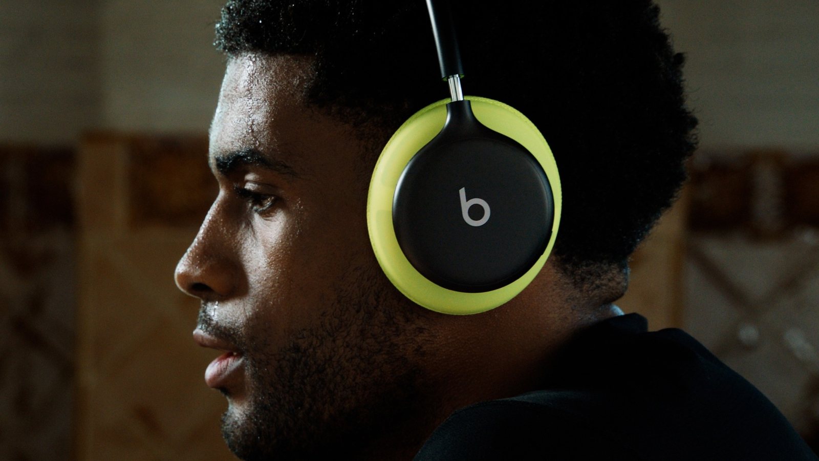 Sportif en sueur de profil portant un casque Beats 360 noir aux coussinets jaune volt